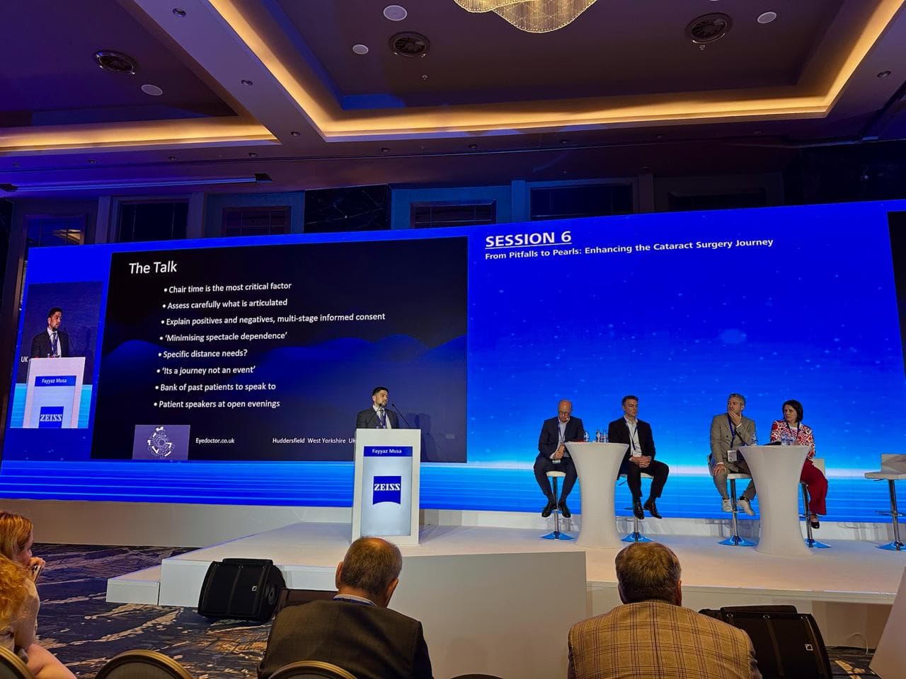 Wide view of the auditorium with Mr Fayyaz Musa at the ZEISS lectern and the session panel seated alongside